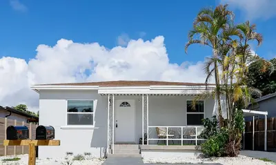 a white house with a palm tree in front of it at La Vie Boheme 1 - Relaxing Retreat w Parking in Miami
