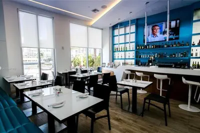 a restaurant with tables and chairs and a bar at Refined Oceanview Apartment, Kitchen, Comfort & Location -A in Hallandale Beach