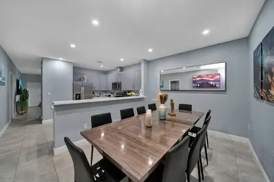 a dining room and kitchen with a wooden table and chairs at Luxury Duplex in Heart of Fort Lauderdale Near The Beach in Fort Lauderdale