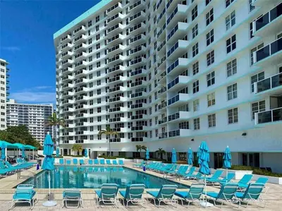 a swimming pool with blue chairs and a large building at Penthouse Beach Front 1st line, 2 BR, 2 BA, New Decoration & Furnitures, unobstructed view of the beautiful Atlantic, free parking in Hollywood