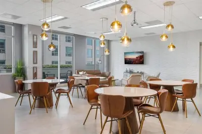 a dining room with tables and chairs and windows at Ocean front private unit in Miami