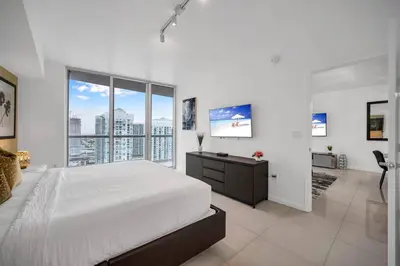 a white bedroom with a large bed and large windows at 38th floor W residence with amenities in Miami
