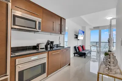 a kitchen with wooden cabinets and a living room at Highest floor Icon W Brickell Location in Miami