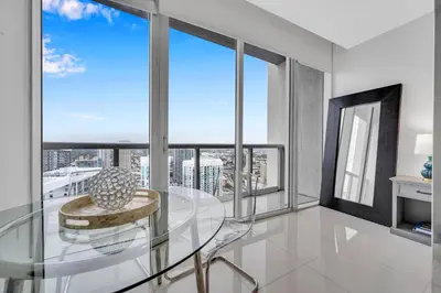 a glass table and chair in a room with windows at Highest floor Icon W Brickell Location in Miami