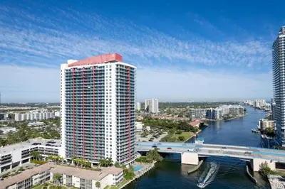 a tall white building next to a river with a bridge at Water View Building With Pool - 5-Min Walk To The Beach in Hallandale Beach