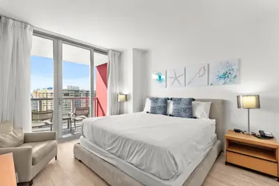 a white bedroom with a large bed and a window at Water View Building With Pool - 5-Min Walk To The Beach in Hallandale Beach