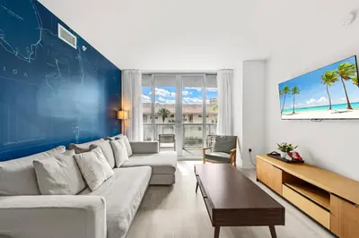 a living room with a white couch and a blue wall at Water View Building With Pool - 5-Min Walk To The Beach in Hallandale Beach