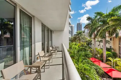 a balcony with chairs and palm trees on a building at Water View Building With Pool - 5-Min Walk To The Beach in Hallandale Beach