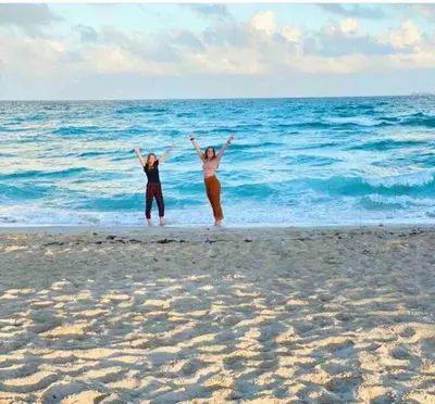 two women standing on the beach with their arms up at Alma Guest Suite in Miami