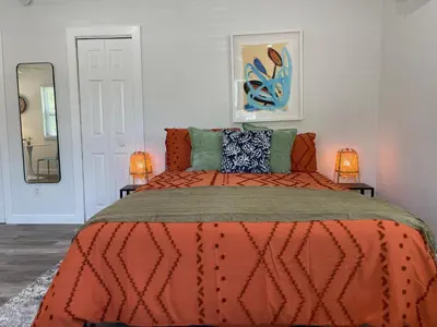 a bedroom with a bed with an orange comforter and two lamps at Casa Habana Studios in Miami