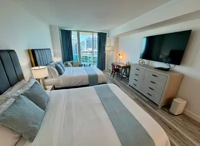 a hotel room with two beds and a flat screen tv at Balcony Ocean View ! WiFi - Pool - Gym - Parking in Miami