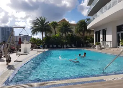 a group of people swimming in a swimming pool at Hallandale Beach, Pool, Gym & More in Hallandale Beach