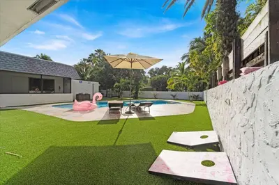 a backyard with a pool and an umbrella and grass at Game & Chill Manor - Arcade - Pool - Pool table in Fort Lauderdale