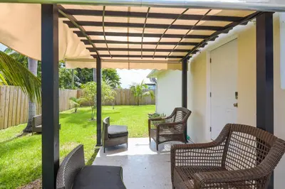 a patio with wicker chairs and an umbrella at Patio and Yard Family-Friendly Miami Oasis! in Miami Gardens
