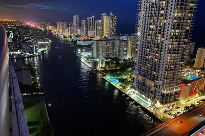 a view of a city at night with a river at 2BR Luxury Stay, Pool, Beach & Mall in Hallandale Beach
