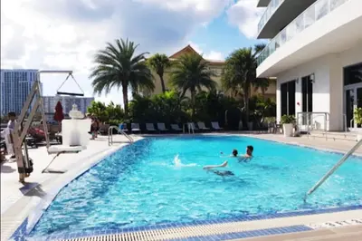 a group of people swimming in a swimming pool at 2BR Luxury Stay, Pool, Beach & Mall in Hallandale Beach