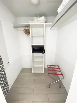 a walk in closet with a shelf and a chair at 2BR Luxury Stay, Pool, Beach & Mall in Hallandale Beach