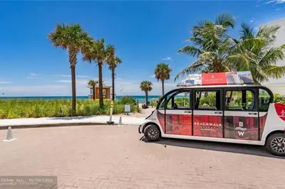 a small car parked next to a beach with palm trees at 2BR Luxury Stay, Pool, Beach & Mall in Hallandale Beach