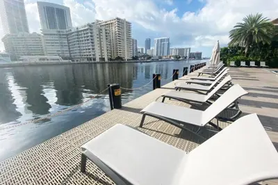 a row of white chairs sitting next to the water at Oceanview 2BR with Beach & Pool -Hallandale in Hallandale Beach