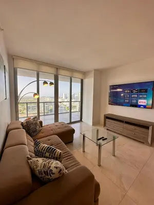 a living room with a couch and a flat screen tv at Oceanview 2BR with Beach & Pool -Hallandale in Hallandale Beach