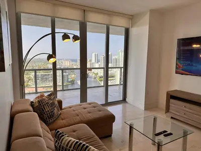 a living room with a couch and a glass table at Oceanview 2BR with Beach & Pool -Hallandale in Hallandale Beach
