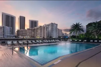 a large swimming pool with chairs and a city skyline at 2 Full Bed BeachWalk Studio, Ocean Nearby, Feels Like Home in Hallandale Beach