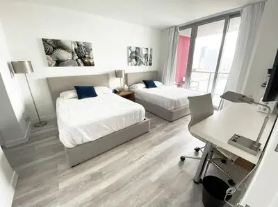 a bedroom with two beds and a desk with a desk at 2 Full Bed BeachWalk Studio, Ocean Nearby, Feels Like Home in Hallandale Beach