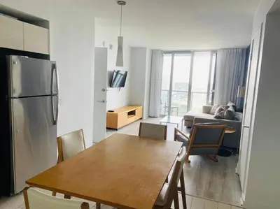 a kitchen and living room with a table and a refrigerator at Oceanfront Elegance, Full Kitchen & Miami Beach Charm -1A in Hallandale Beach