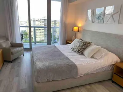 a bedroom with a large bed and a chair at Seaside Retreat in Miami, Full Kitchen & Balcony Views -A in Hallandale Beach