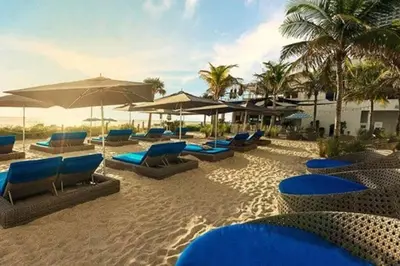 a beach with blue lounge chairs and umbrellas at Ocean Air & 2 Cozy Full Beds, Relaxing Beach Studio in Hallandale Beach