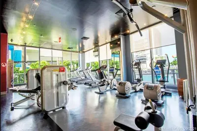 a gym with a bunch of treadmills and machines at Chill Out in This Stylish 2-Full Bed BeachWalk Studio in Hallandale Beach