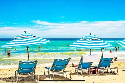 a group of chairs and umbrellas on a beach at Sunny Studio Stay, 2 Full Beds, Coastal Walks Nearby in Hallandale Beach