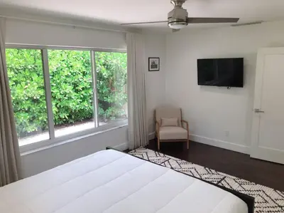 a bedroom with a bed and a television and a chair at Villa Palma-Hollywood Beach-Private Pool & Beachwalk! in Hollywood