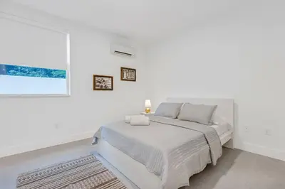 a white bedroom with a bed and a window at Up to 16 guests! Modern house near Wynwood in Miami