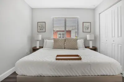 a white bedroom with a large bed with a wooden tray on it at Sistrunk Shades Villas #1 - Brand New Townhomes Downtown Fort Lauderdale in Fort Lauderdale