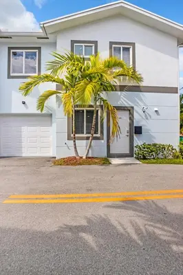 a palm tree in front of a white house at Sistrunk Shades Villas #3 - Brand New Townhomes Downtown Fort Lauderdale in Fort Lauderdale