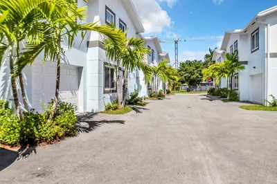 a street with palm trees in front of white buildings at Sistrunk Shades Villas #3 - Brand New Townhomes Downtown Fort Lauderdale in Fort Lauderdale