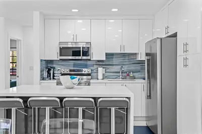 a kitchen with white cabinets and a stainless steel refrigerator at Luxury Vacation House in Miami’s Center! in Miami