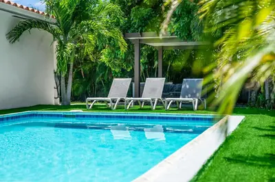 a swimming pool with two lounge chairs next to a house at Luxury Vacation House in Miami’s Center! in Miami