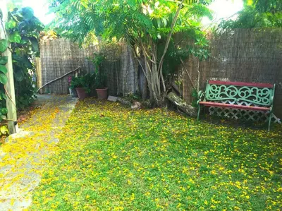 a red bench sitting in a yard with yellow flowers at Miami Bungalow Oasis near Everglades & The Keys in Cutler Bay
