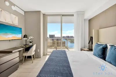 a bedroom with a bed and a desk and a large window at Wrap Around Balcony Insane Views Amazing Pools in Hollywood