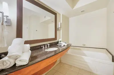 a bathroom with a sink and a mirror and a tub at 21st Floor Luxury Suite at Trump Int Resort in Miami Beach