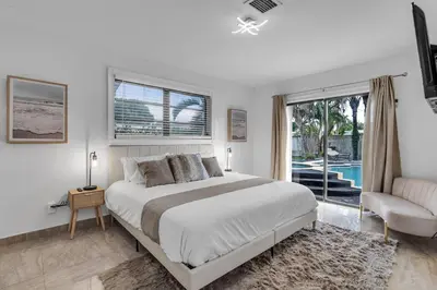 a bedroom with a bed and a couch and a window at Heated Pool Tropical Backyard 3 Bedrooms, 12 min to the Ocean in North Miami Beach