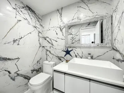 a bathroom with a white sink and a mirror at Beach Paradise a cozy ocean view condo on the beach with free parking in Hollywood
