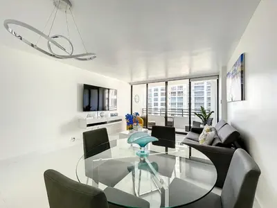 a white living room with a glass table and chairs at Beach Paradise a cozy ocean view condo on the beach with free parking in Hollywood