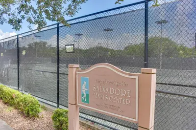 a sign in front of a fence with a tennis court at Refreshing Miami Apartment 4 Mi to the Beach! in Miami