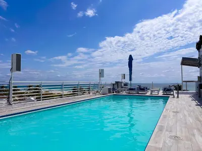 a swimming pool on top of a building with the ocean in the background at Rooftop-Pool King Bed Suite on Ocean Dr C305 in Miami Beach
