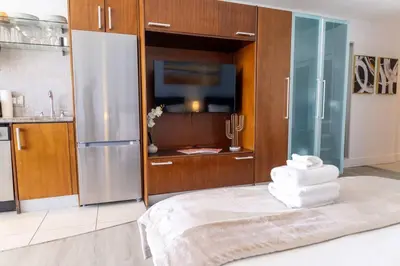 a kitchen with a refrigerator and a pile of towels at Rooftop-Pool Suite on Ocean Dr C505 in Miami Beach