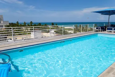 a large swimming pool with the ocean in the background at Rooftop-Pool Suite on Ocean Dr C505 in Miami Beach