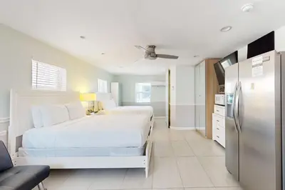 a white bedroom with a bed and a refrigerator at Hollywood Bungalow in Hollywood